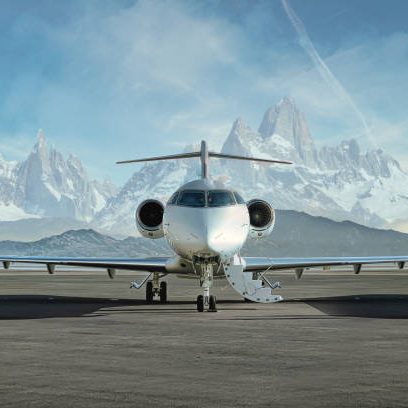 Head on photo of a private jet waiting on runway to be boarded with snowy mountains in the background